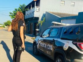 Policial civil ao lado de viatura da PCMG.