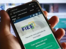 Mãos que seguram um celular mostrando o site do Fies