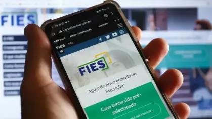 Mãos que seguram um celular mostrando o site do Fies